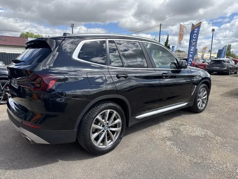 BMW X3 xDrive30e 2023 en saphirschwarz métallisé, vue 3/4 arrière droit avec jantes alu 19 pouces et attelage électrique.