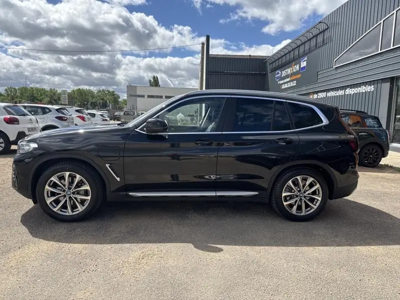 BMW X3 xDrive30e noir saphir métallisé vue de profil côté gauche avec jantes alliage 19 pouces et toit panoramique.