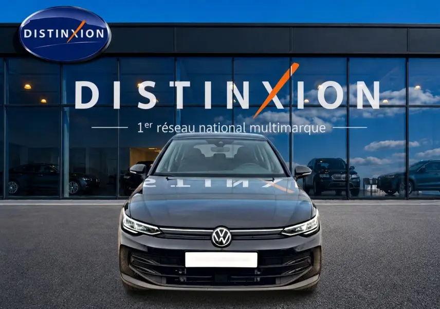Vue frontale d'une Volkswagen Golf noire 2026 garée devant une vitrine avec logo Distinxion en arrière-plan.