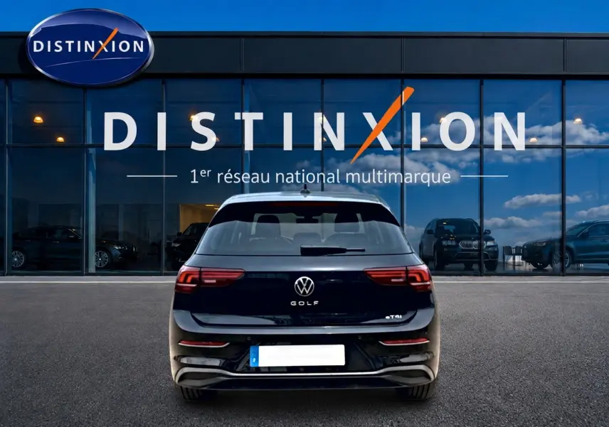Vue arrière d'une Volkswagen Golf noire 2026 garée devant une vitrine avec logo Distinxion.