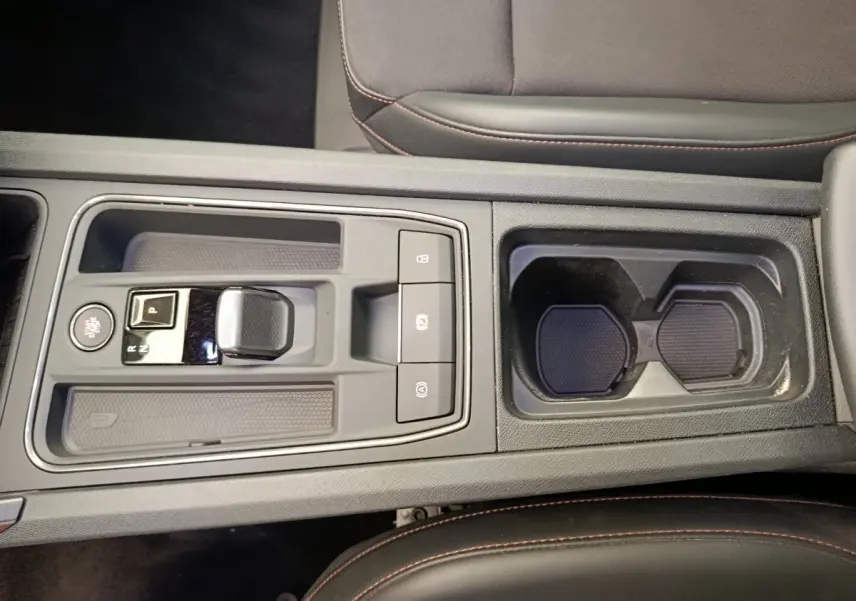 Vue plongeante sur la console centrale grise foncé de la CUPRA LEON ST 2024 avec levier de vitesse automatique et porte-gobelets.