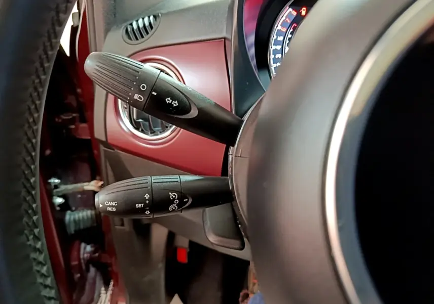 Gros plan sur les commandes au volant et tableau de bord rouge d'une Fiat 500 1.0 70ch BSG Star essence hybride 2021.