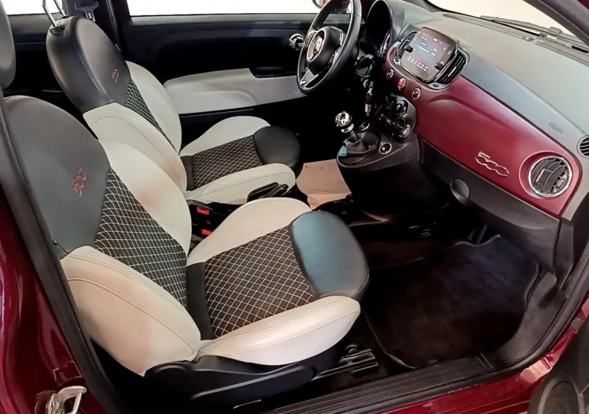 Intérieur avant droit de la FIAT 500 rouge 2021 avec sièges bi-ton, tableau de bord assorti et écran tactile.
