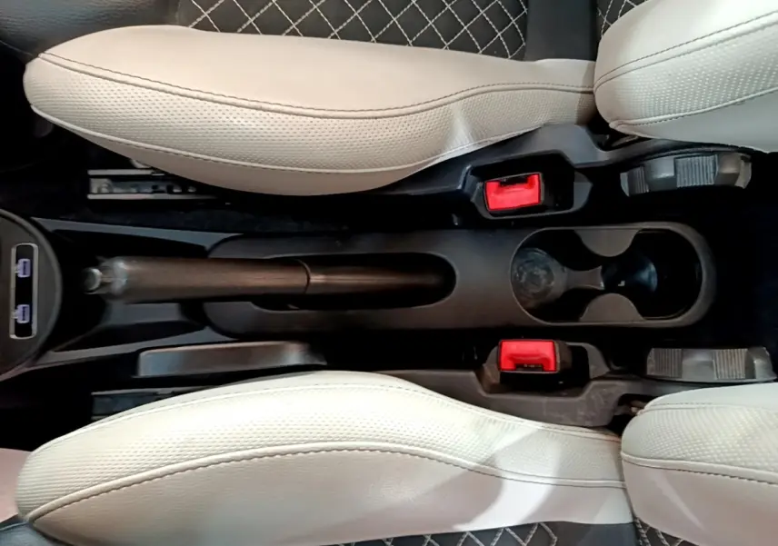 Vue plongeante sur la console centrale noire entre les sièges beige clair d'une Fiat 500 1.0 hybride, avec frein à main manuel et deux porte-gobelets.