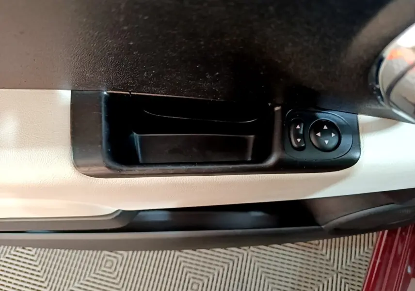 Poignée intérieure côté gauche avec commandes des rétroviseurs sur porte beige d'une FIAT 500 rouge 2021.