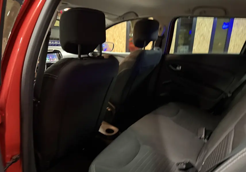 Vue intérieure arrière droite de la Renault Clio Estate IV rouge de 2015, montrant les sièges arrière et avant en tissu noir.