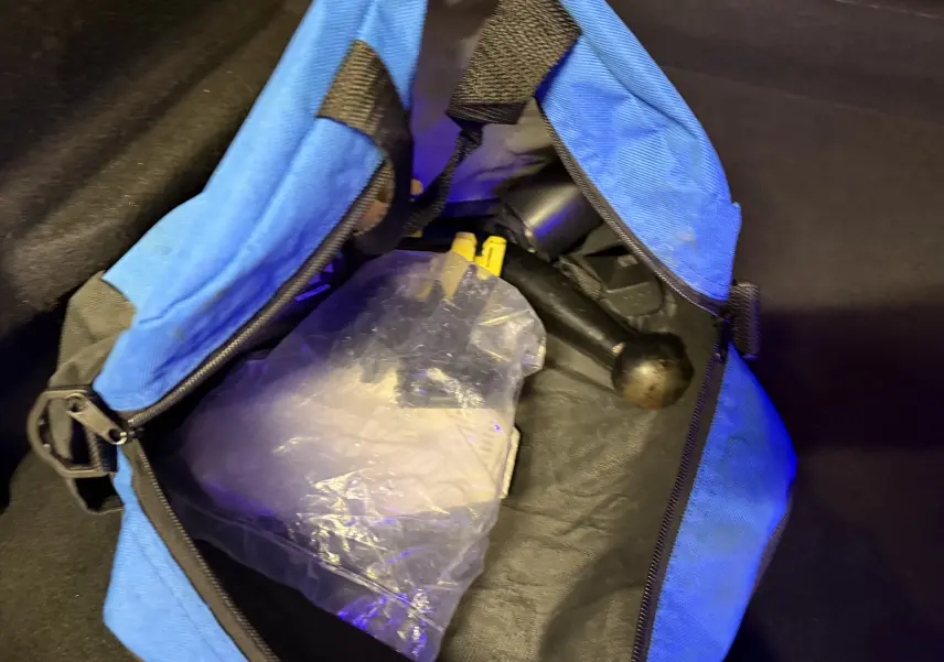 Sac bleu ouvert montrant une boule d'attelage noire et un emballage plastique, accessoires pour Renault Clio Estate IV rouge.