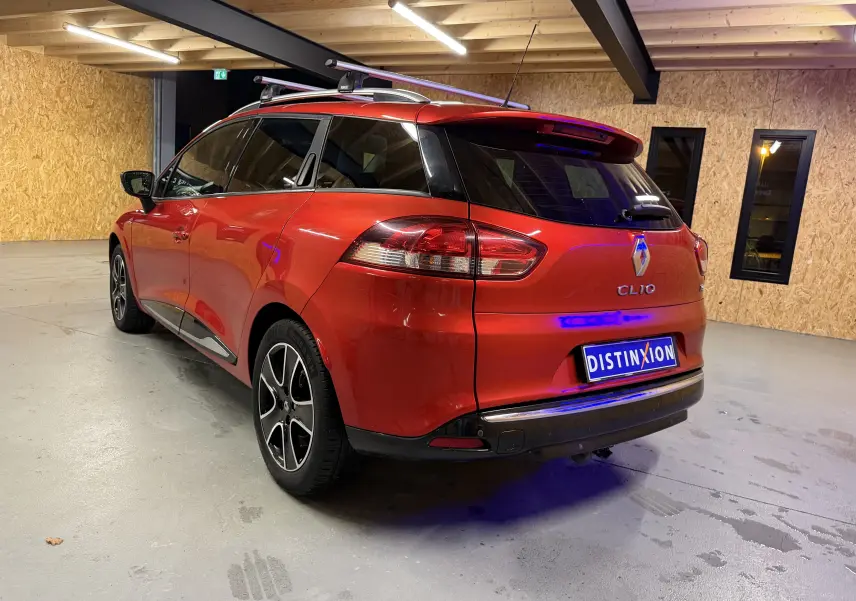 Renault Clio Estate IV rouge vue 3/4 arrière droit dans un garage avec attelage et barres de toit.