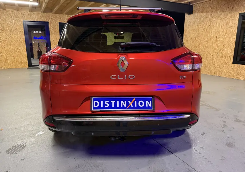 Vue arrière d'une Renault Clio Estate IV rouge avec attelage et logo TCe visible dans un garage.