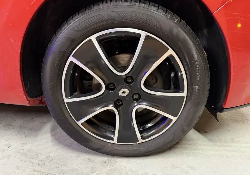 Gros plan sur la roue avant droite rouge d'une Renault Clio Estate IV avec jante noire et argentée au design moderne.