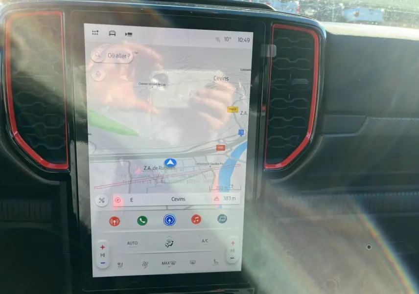 Écran tactile central du Ford Ranger Raptor 2025 avec navigation, entouré de grilles d’aération rouges et tableau de bord noir.