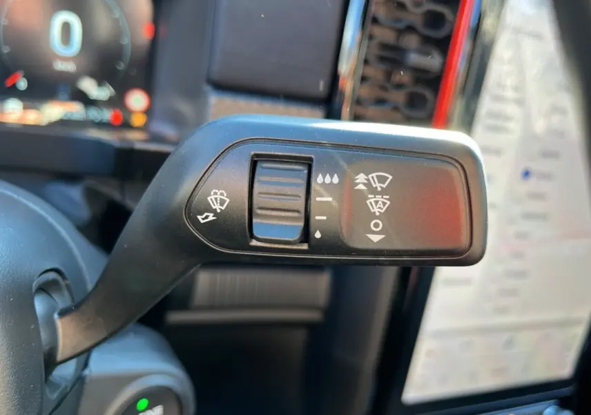 Gros plan sur la commande des essuie-glaces à gauche du volant dans l'habitacle du Ford Ranger Raptor gris commandeur.