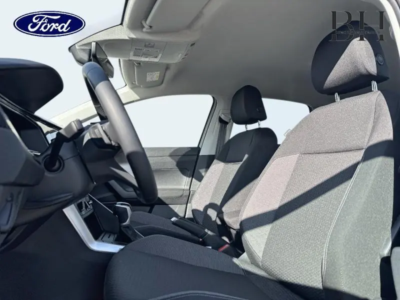 Vue intérieure côté conducteur du Volkswagen Taigo 2024, sièges tissu noir et console centrale avec levier de vitesse.