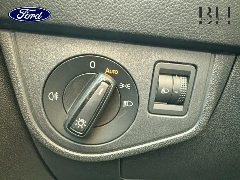Gros plan sur la commande des phares d’un Volkswagen Taigo blanc Pur, avec réglage automatique et manuel.