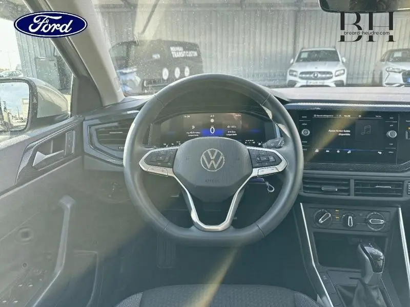 Vue intérieure du tableau de bord et volant cuir multifonction du Volkswagen Taigo blanc, avec écran tactile et commandes au volant.