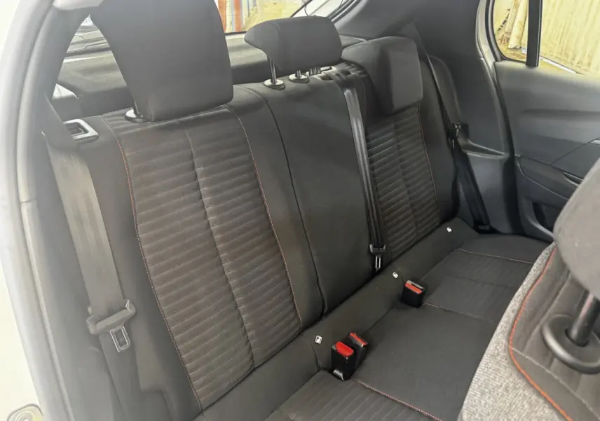 Vue intérieure côté arrière droit montrant la banquette noire avec surpiqûres rouges de la Peugeot 208 blanche 2020.