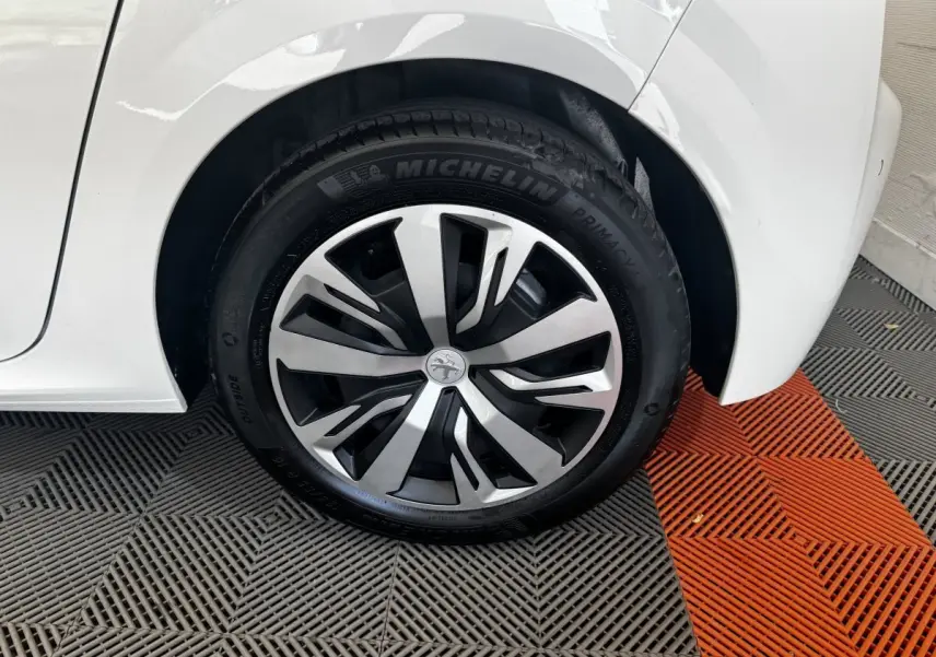 Gros plan sur la roue arrière droite blanche d’une Peugeot 208 avec jante alliage et pneu Michelin.