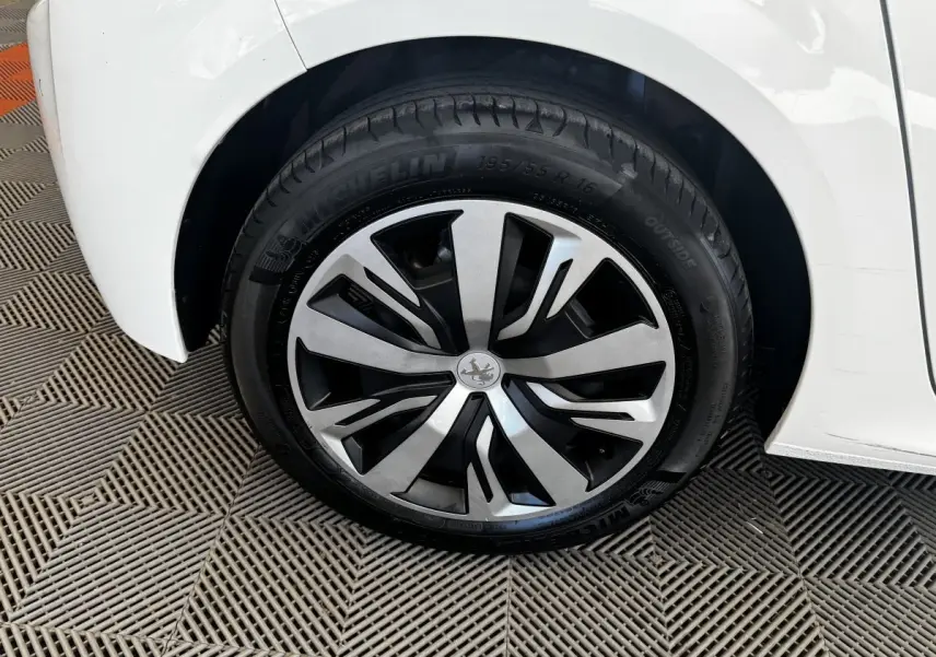 Gros plan sur la roue arrière droite de la Peugeot 208 blanche, avec jante alliage au design moderne.