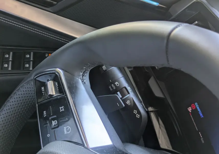 Vue rapprochée du volant et de la porte côté conducteur du Renault Austral 2025, avec éclairage d'ambiance bleu.