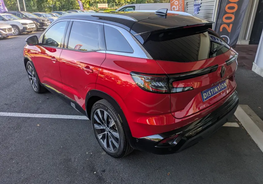 Vue 3/4 arrière droite du Renault Austral rouge Flamme avec toit panoramique noir et jantes alliage bicolores.