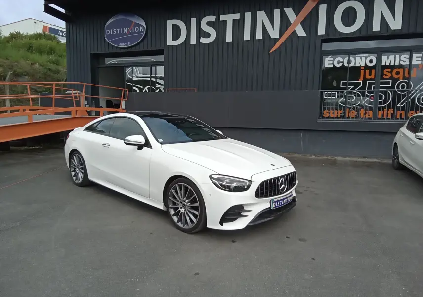 Mercedes Classe E Coupé 220D AMG Line blanc vu en 3/4 avant droit, avec calandre AMG et jantes alliage 19 pouces.