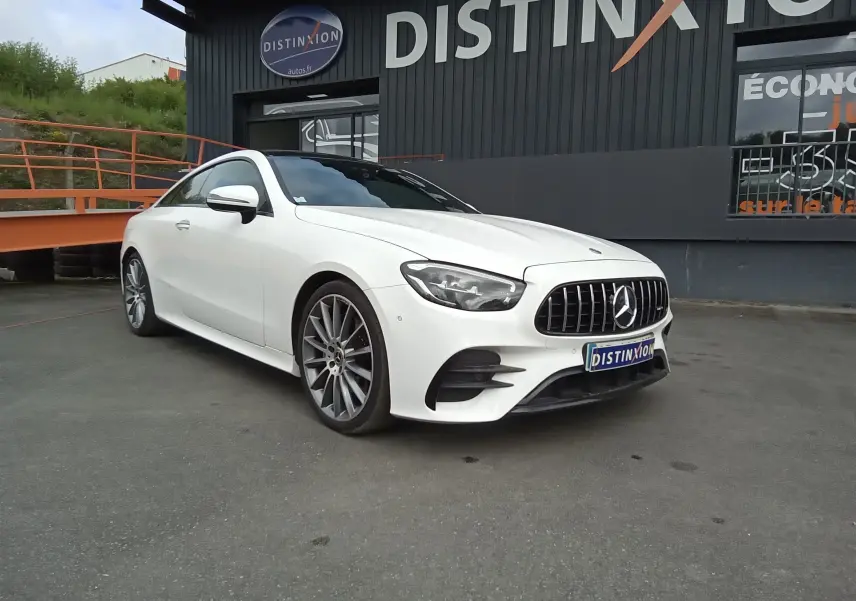 Mercedes Classe E Coupé 220D AMG Line blanc vu en 3/4 avant droit, avec calandre verticale et jantes alliage 19 pouces.