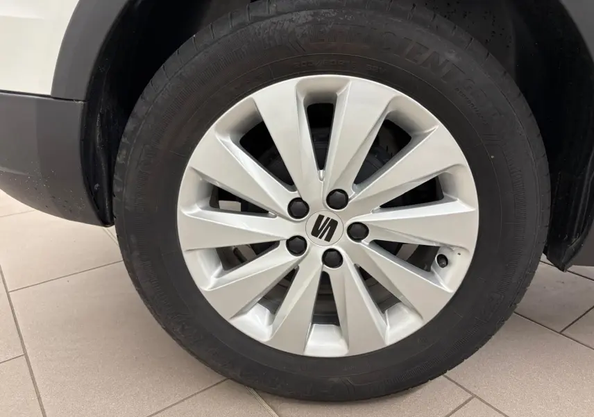 Gros plan sur la roue avant droite d'une SEAT Arona 2023 blanc toit noir avec jante argentée à dix branches.