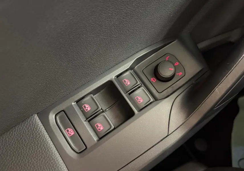 Gros plan sur les commandes de lève-vitres et réglage des rétroviseurs côté conducteur du SEAT Arona blanc toit noir 2023.