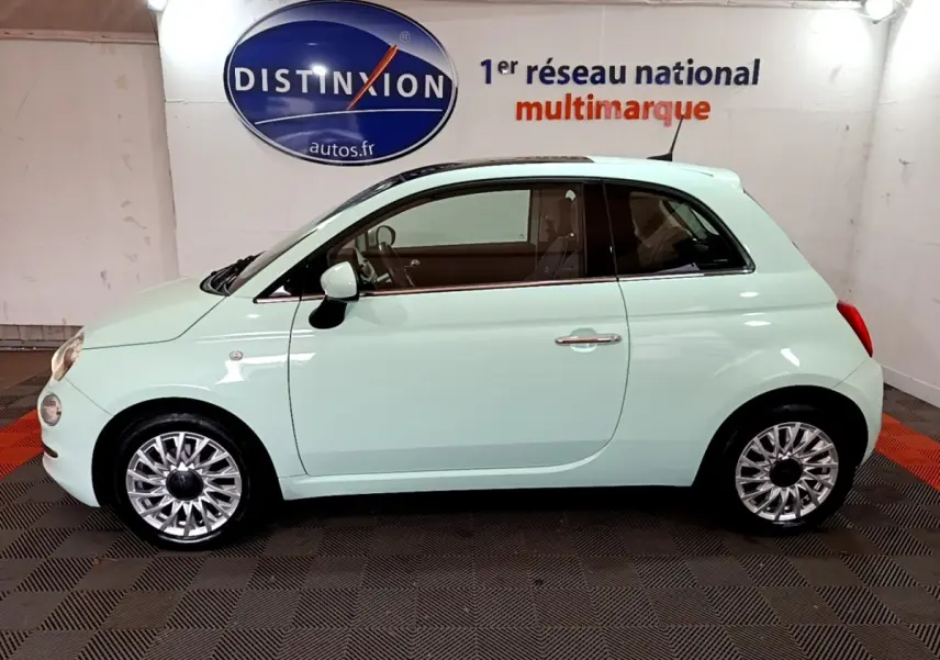 Profil côté gauche d'une FIAT 500 Lounge 2019 vert clair avec jantes alliage et toit noir en intérieur showroom.