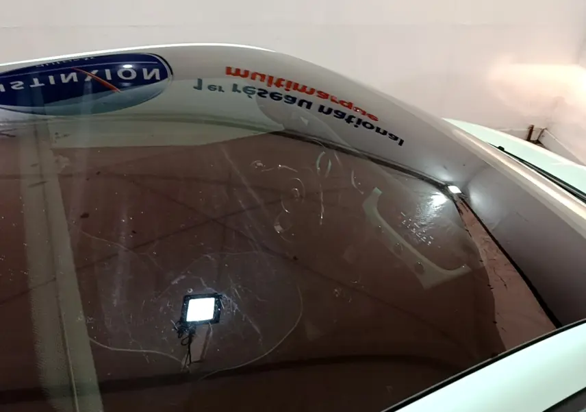 Vue plongeante sur l'intérieur d'une FIAT 500 verte, mettant en valeur le tableau de bord et le volant visibles à travers le pare-brise.