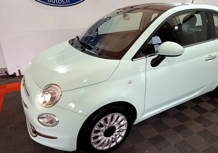 Vue 3/4 avant droit d'une FIAT 500 Lounge 2019 vert clair avec toit noir et jantes alliage multibranches.
