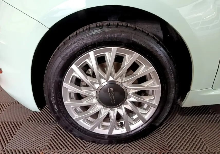 Gros plan sur la roue avant gauche argentée d'une FIAT 500 verte 2019 avec jante à rayons fins.