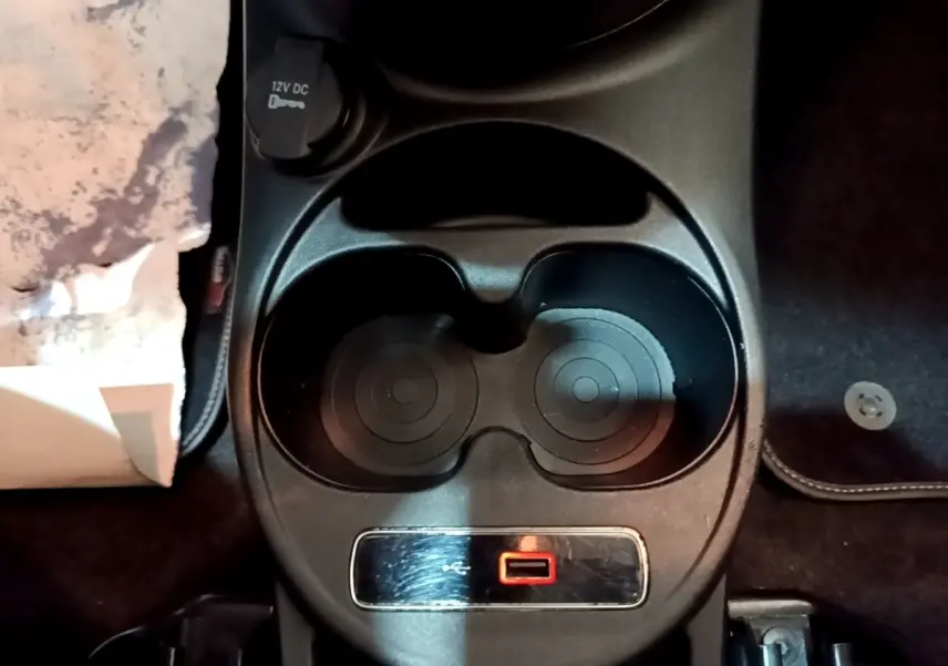 Vue rapprochée de la console centrale noire de la Fiat 500 Lounge 2019 avec prise 12V et porte-gobelets.