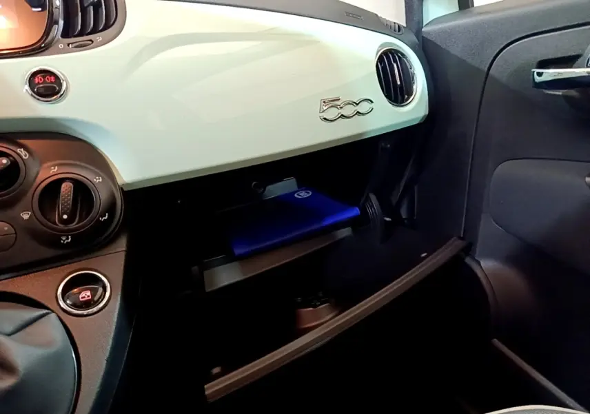 Intérieur de la Fiat 500 2019, tableau de bord vert clair avec boîte à gants ouverte côté passager.
