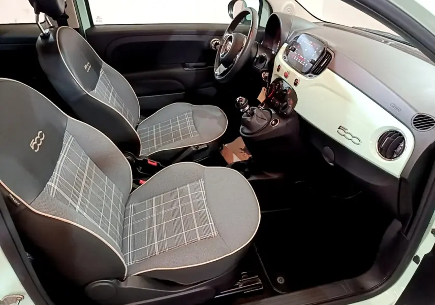Vue intérieure côté conducteur de la Fiat 500 Lounge 2019, montrant les sièges gris à motif à carreaux et le tableau de bord clair.