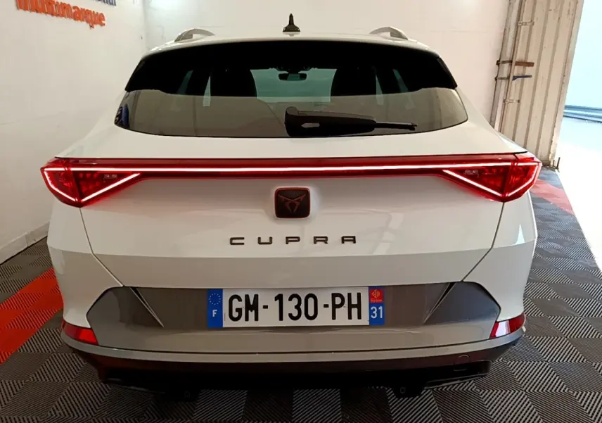 Vue arrière d'une CUPRA Formentor blanche avec feux LED reliés par une barre lumineuse rouge.