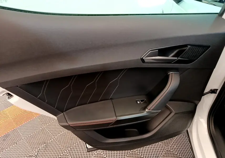 Gros plan sur la porte avant droite blanche du CUPRA Formentor 2023, avec garniture noire et surpiqûres rouges.