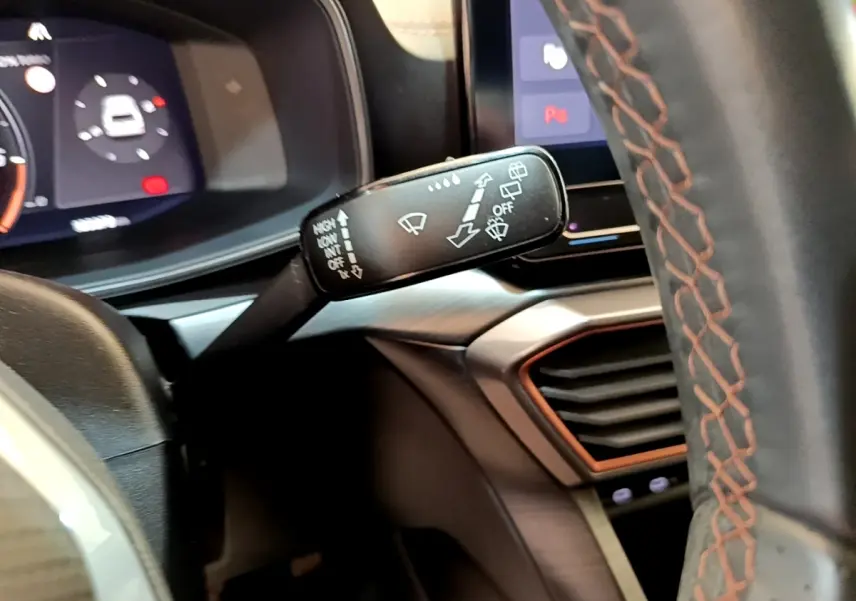 Gros plan sur la manette d’essuie-glace à gauche du volant cuir noir avec surpiqûres orange du CUPRA Formentor 2023.