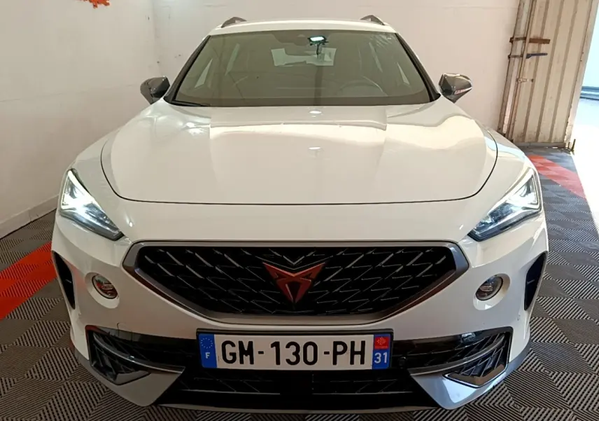 Vue avant d'un CUPRA Formentor blanc avec calandre noire et logo orange, phares LED allumés en intérieur.