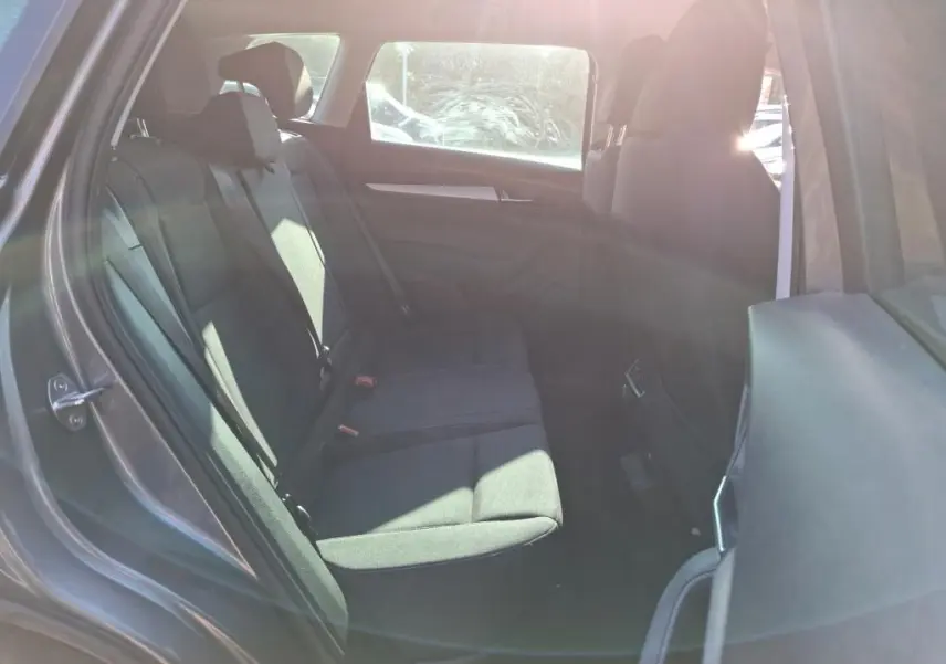 Vue intérieure côté droit des sièges arrière noirs du Skoda Karoq gris 2023 avec ceintures visibles et lumière naturelle.