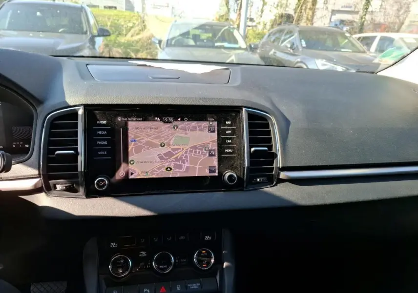 Vue intérieure du tableau de bord du Skoda Karoq gris 2023, avec écran tactile multimédia affichant la navigation.