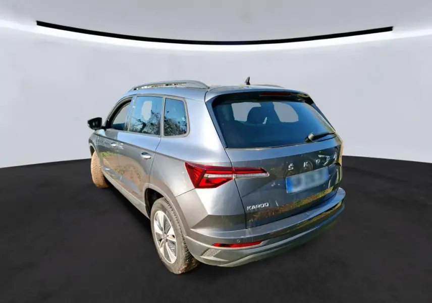Vue 3/4 arrière droite d'un Skoda Karoq gris 2023 avec jantes alu 17 pouces et feux arrière LED distinctifs.