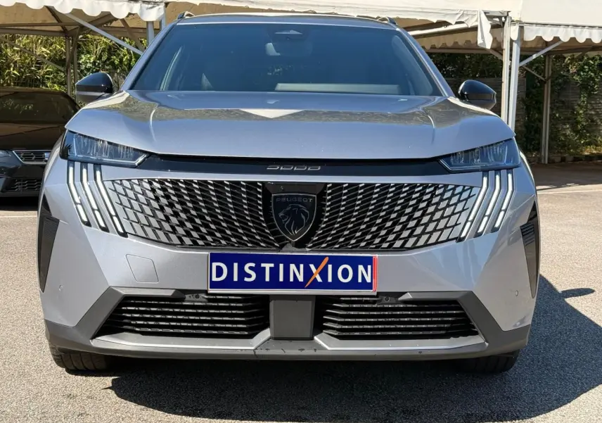 Vue frontale d'un Peugeot 5008 gris Artense avec calandre distinctive et feux LED en griffes verticales.