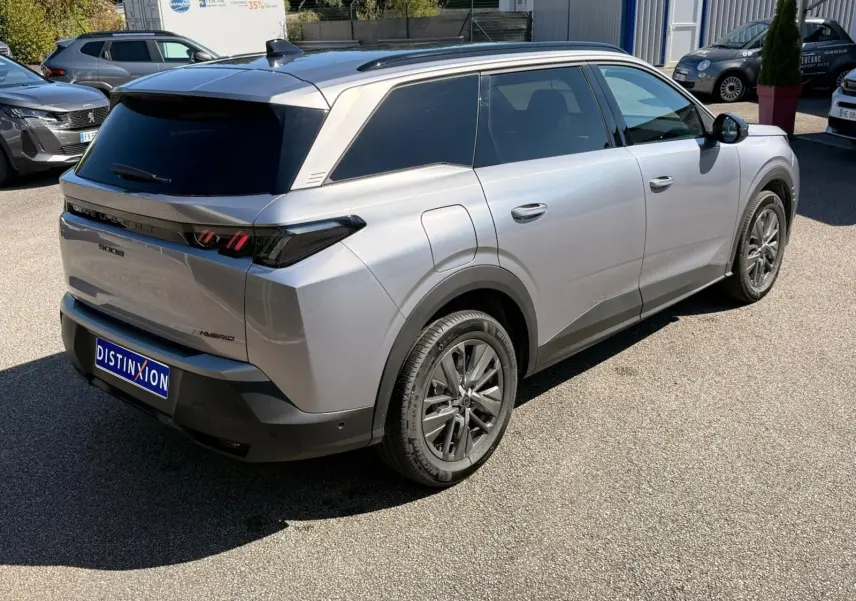 Vue 3/4 arrière droite d’un Peugeot 5008 gris Artense hybride 2025 avec vitres teintées et jantes alliage.