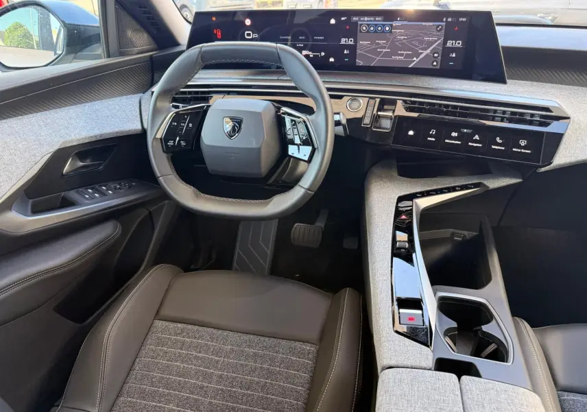 Vue intérieure de face du poste de conduite du Peugeot 5008 2025, volant compact et tableau de bord numérique large.