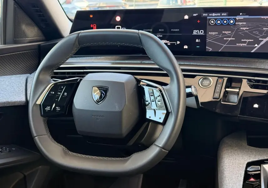 Vue intérieure centrée sur le volant cuir du Peugeot 5008 2025, avec tableau de bord numérique et écran tactile intégré.