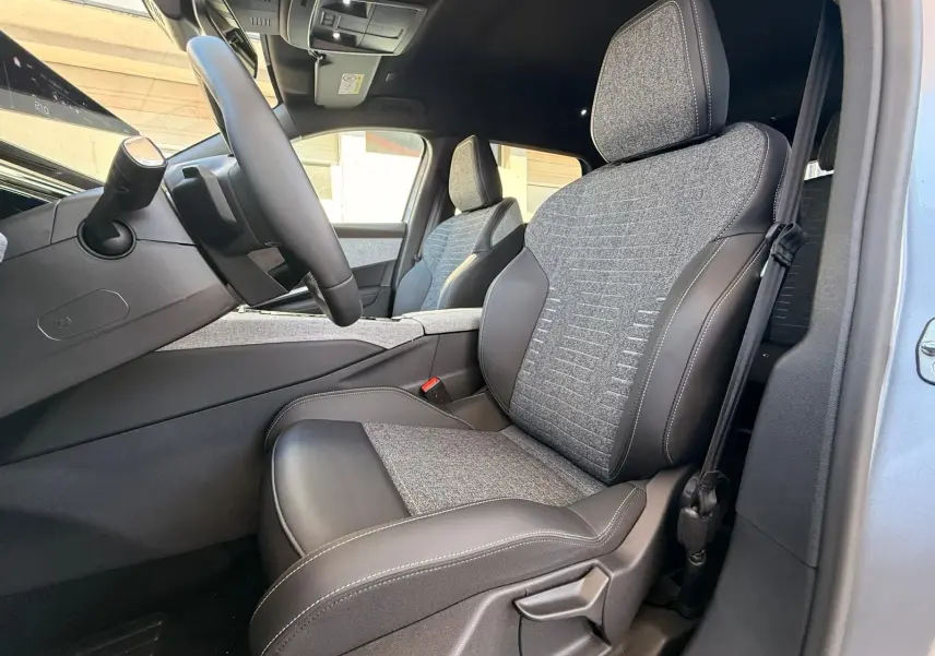 Vue intérieure côté conducteur du Peugeot 5008 1.2 Hybrid 145 Allure, sièges tissu gris et cuir noir.
