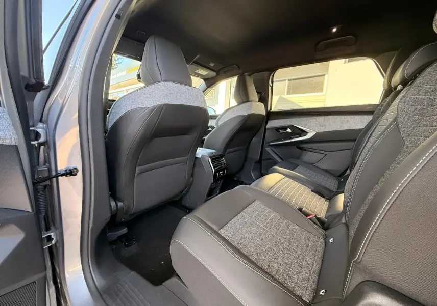 Vue intérieure arrière côté gauche du Peugeot 5008 gris Artense 2025, sièges tissu et cuir avec surpiqûres blanches.