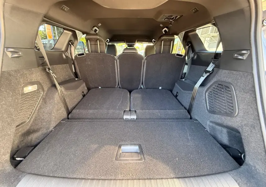 Vue intérieure arrière du coffre du Peugeot 5008 gris Artense avec sièges arrière rabattus, montrant un espace de chargement plat.