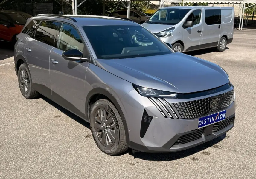 Peugeot 5008 gris Artense en 3/4 avant droit, mettant en valeur sa calandre distinctive et ses feux LED fins.